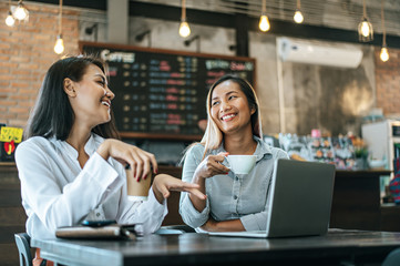 Two women sitting and working with a laptop in a coffee shop