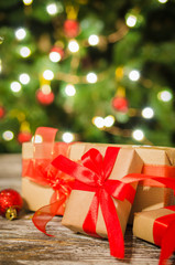 Christmas gift boxes against the background of Christmas tree and bokeh of twinkling party lights.