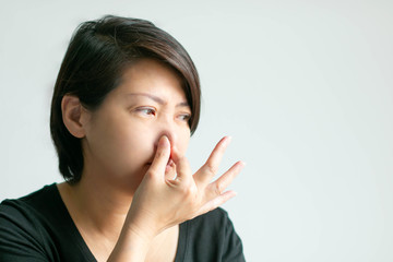 A woman use thumb and forefinger pinch her nose when scent bad smell. - obrazy, fototapety, plakaty