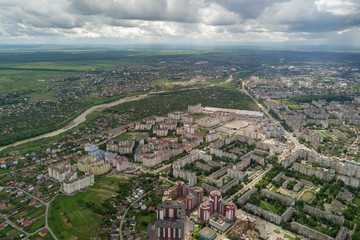 Aerial view of town or city with rows of buildings and curvy streets in summer. Urban landscape from above.