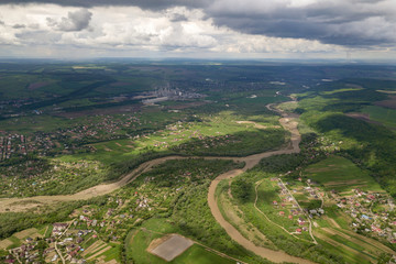 Fototapeta na wymiar Aerial view of town or village with rows of buildings and curvy streets between green fields in summer. Countryside landscape from above.