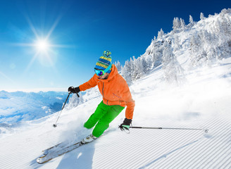 Skier skiing downhill during sunny day in high mountains