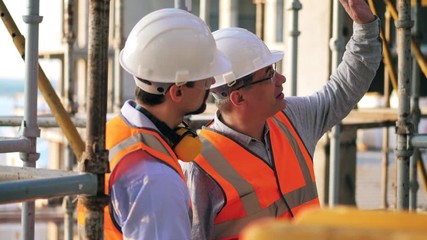 Male engineers are talking while observing construction site
