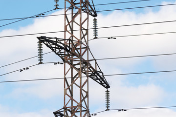 High-voltage technological power lines on metal poles with powerful power wires against the sky