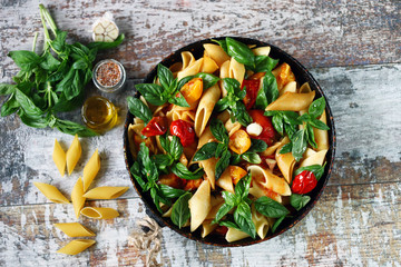 Appetizing pasta in a pan with tomatoes, basil and spices. One pan pasta. Italian vegan pasta....