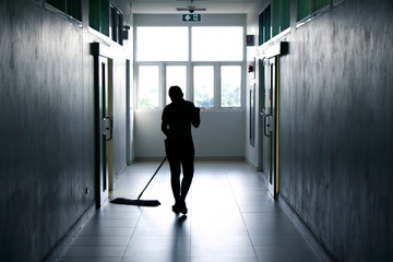 Janitor woman mopping floor in hallway office building or walkway after school and classroom silhouette work job background.