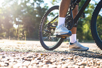 Naklejka premium A low perspective of mountain cyclists on a rocky path at sunset Focus on shoes
