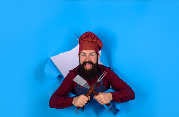 Chef man with BBQ cooking tools. Barbecue chef looking through paper hole. Picnic&barbecue. Cooking meat in park. Barbecue master. Chief cook in workwear with utensils for barbecue grill. Grill cook.