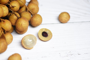 Longan fresh tropical fruit and green leaf in Thailand / Dimocarpus longan and peel exotic fruits on white wooden
