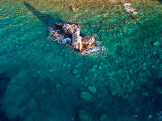 Naklejka na ściany i meble Aerial view of a seabed with rocks emerging from the sea, seabed seen from above, transparent water