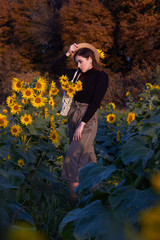  Beautiful lovely girl in a straw hat holding a wicker bag with flowers. Enjoying nature on a sunny field of sunflowers. Autumn time. The concept of happiness, tranquility, love of life.