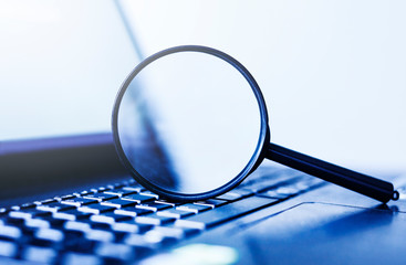Laptop computer with magnifying glass, concept of search