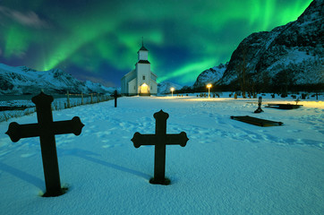 Northern lights over winter landscape with church and graveyard