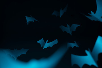 Halloween image of blue paper bats on dark blue background.