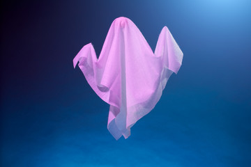 Picture of halloween pink ghosts from white fabric on blue background