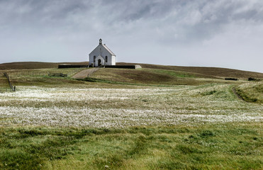 Lone Stonybreck village church, on Fair Isle island in Shetland with floral meadow and dramatic​ sky © Samuel