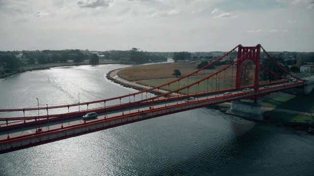 Suspended bridge red colored over the sea. Transportation of traffic over the suspended bridge. Aerial view, 4k.