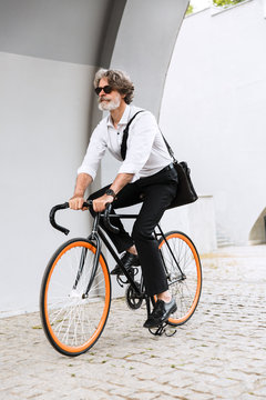 Photo of caucasian elderly businessman riding bicycle