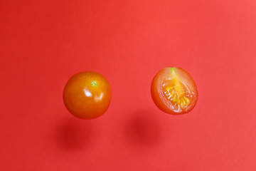 Ripe fresh cherry tomatoes - whole and half - on a red background. Zero gravity banner. Levitation....