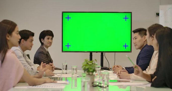 Creative business team looking at green screen in the conference room applaud spokesperson.