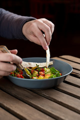 Young man is having a light meal with warm seasonal salad with baked jacket potato, served with flat bread