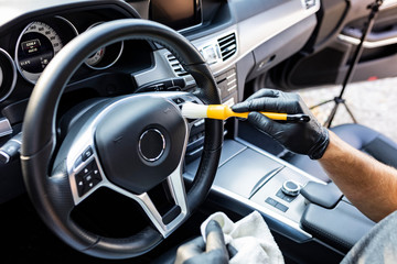 Car detailing. Vacuuming and cleaning of nooks on the dashboard and at the car steering wheel