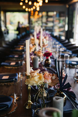 Wedding table setting for celebration of marriage and love with flowers and floral arrangement plus silverware, dinnerware, glassware, and luxurious romantic decor.