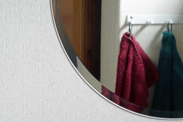 Round shape mirror and reflection of two towels which hanging on the wall. Copy space.