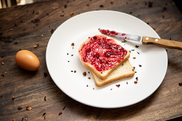 breakfast with bread and berry jam on a white plate