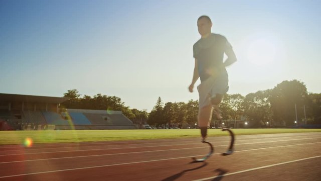 Athletic Disabled Fit Man with Prosthetic Running Blades is Training on a Outdoors Stadium on a Sunny Afternoon. Amputee Runner Jogging on a Stadium Track. Motivational Sports Footage. Tracking Shot.