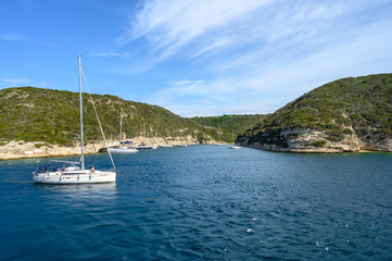 Panoramic view of the bay with mountains against blue sky with clouds. White yacht in the foreground