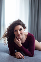 Young woman in a red bodysuit relaxing in bed.