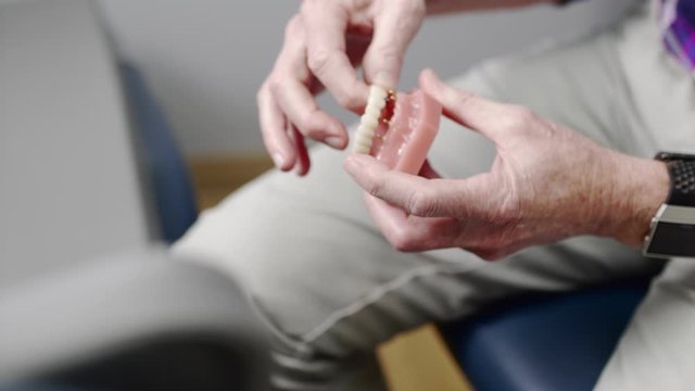 Dentist demonstrating how dentures can be mounted with implants