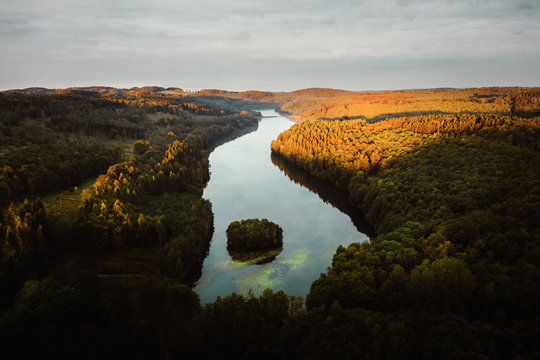 See von oben im Licht vom Sonnenaufgang auf Wald mit kleiner Insel mit B&auml;umen im Vordergrund in Deutschland