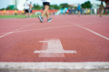 Abstract texture and background of empty running track with number one on the floor and defocused people  exercising in background