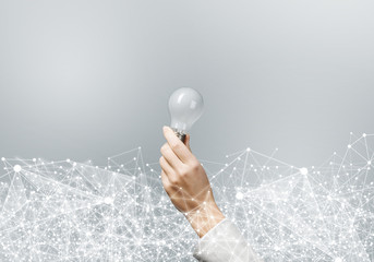 Woman hand holding light bulb and abstract network