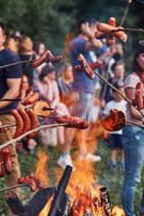 People roasting sausages and bread over a bonfire during picnic party on summer vacation day. Real people, authentic situations