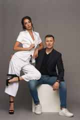 Young adult casual dressed couple hugging and posing against gray background. Caucasian handsome man and pretty beautiful woman with hairstyle. Love