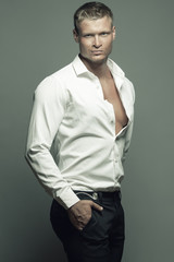 Male fashion, beauty concept. Portrait of brutal young man with short wet blond hair wearing white...