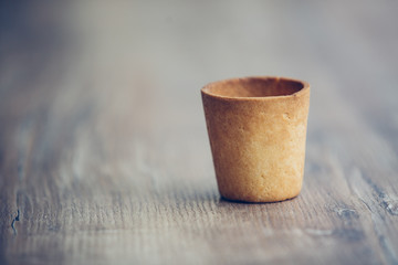 Emptywaffle cup for ice-cream on the wooden table in cafe .Wafer cup for ice-cream  with space for text. cup of sand dough.cardboard coffee cup on wooden table with space for text
