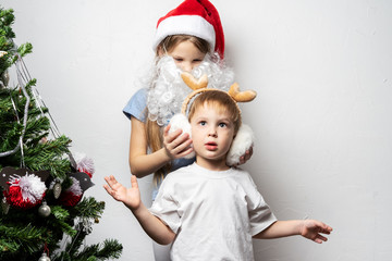 Boy and a girl in a Santa cap decorate a Christmas tree. Family portrait.