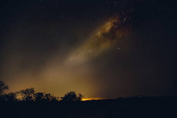 Fototapeta na wymiar The milky way over the greater kruger with the warm glow of a local community