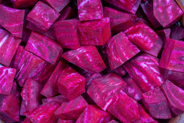 Obraz na płótnie Canvas Fresh segments of a red beetroot, closeup. Purple beet slices background, top view