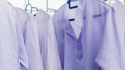 Close up view of the white school uniform for the students drying under the sun on the outdoor clothes hanger.