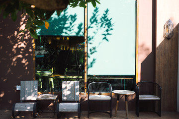 wooden chairs beside glass wall with sun light and leave shadow