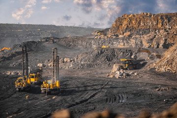 Open coal mine. Drilling machine borer installing cast explosives blasting