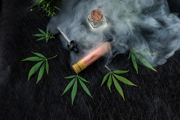 Cannabis liquid. Vape CBD or THC, Vaping Marijuana and Hemp. Against a Dark Background. Puffs of...