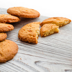 Round orange biscuits with colorful candied fruits and a slice of juicy orange lying on a wooden table against the background of winter forest
