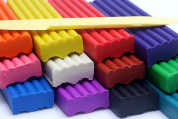 Multicolored set of plasticine sticks and sculptural knife on white background closeup view.