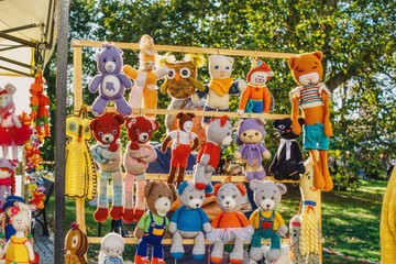 różnokolorowe lalki przytulanki wystawione na jarmarku do sprzedaży - obrazy, fototapety, plakaty